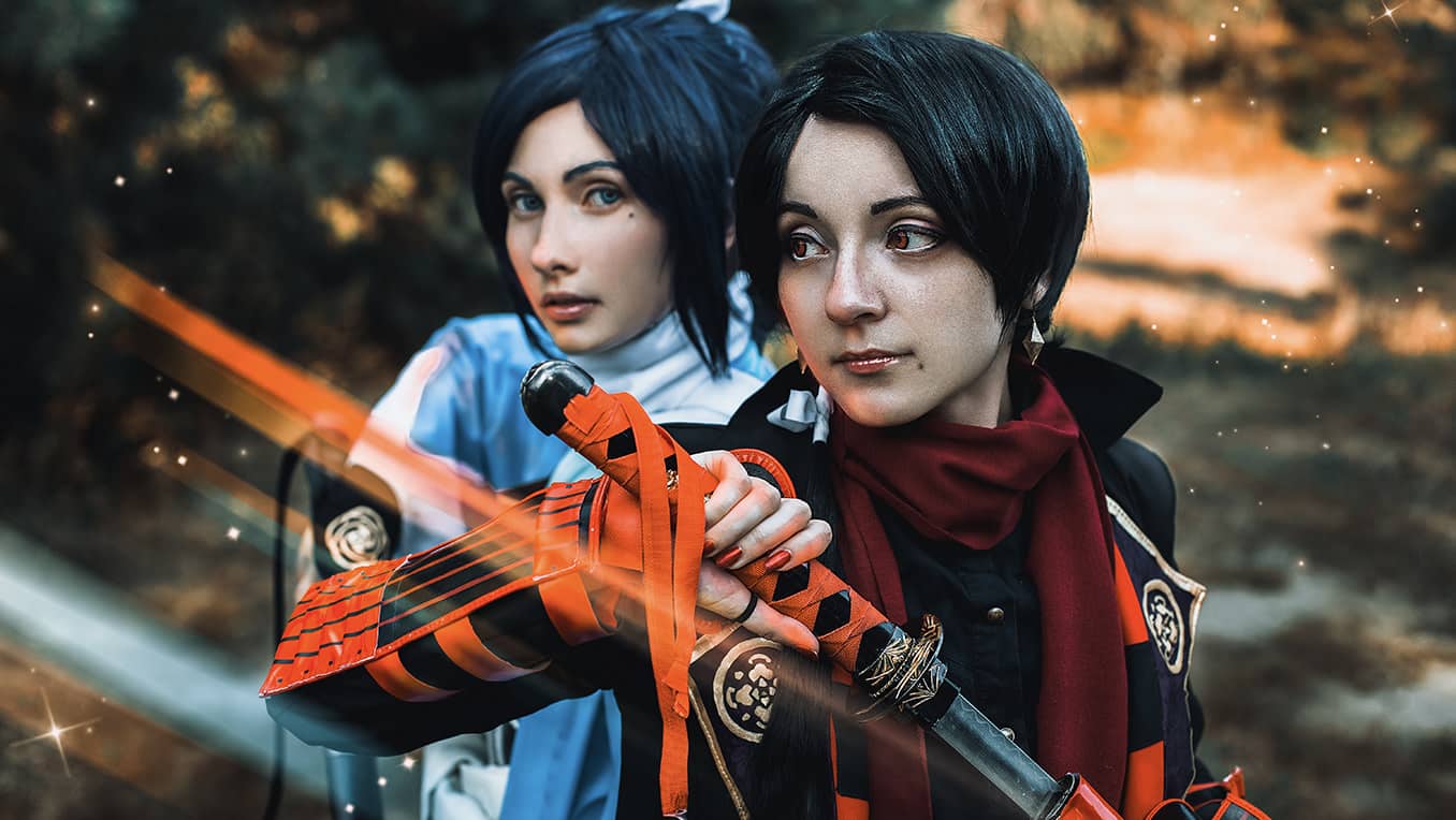 Two women cosplaying as futuristic samurai holding katanas, dressed in orange and blue
